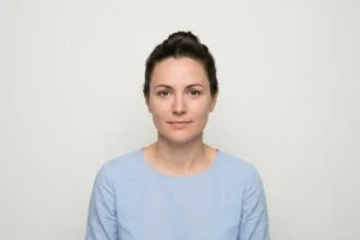 Femme en train de prendre une photo d'identité pour son dossier de permis de conduire sur fond blanc