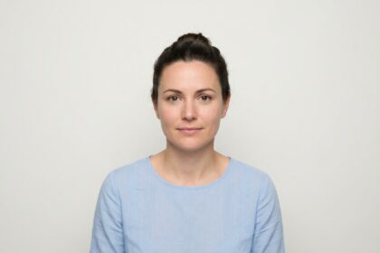 Femme en train de prendre une photo d'identité pour son dossier de permis de conduire sur fond blanc
